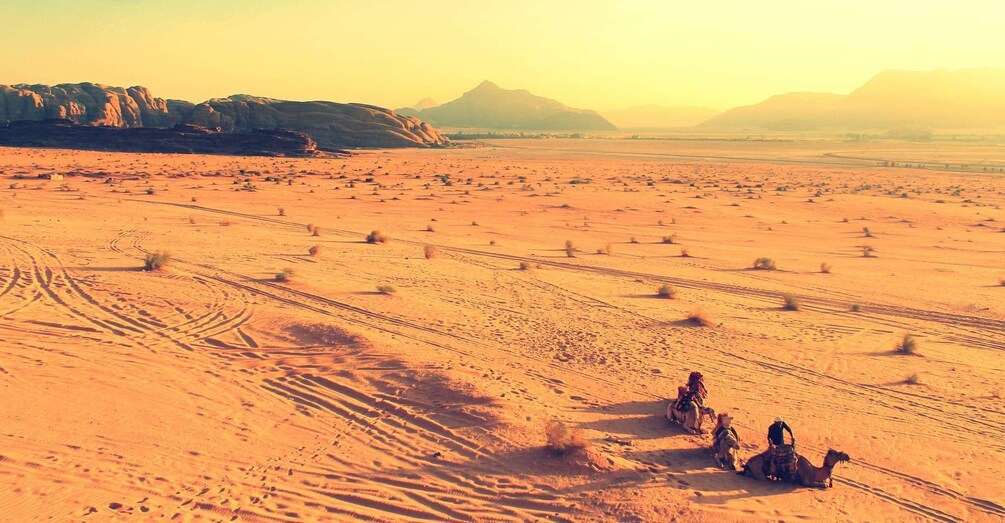 A desert landscape with camel riders and camels. 4