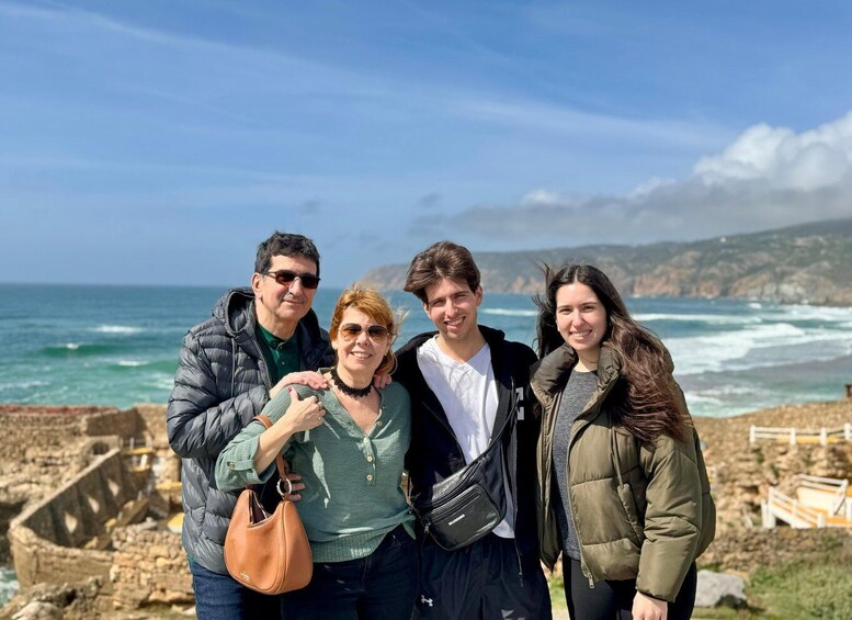 Un grupo de personas de pie sobre una costa rocosa, con el océano al fondo. 2