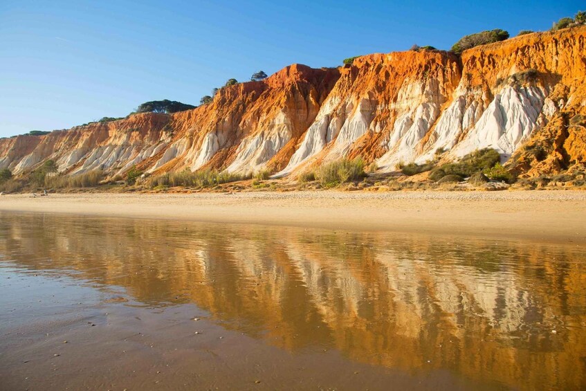 Un paisaje costero con una playa arenosa y acantilados con formaciones rocosas estratificadas. 3