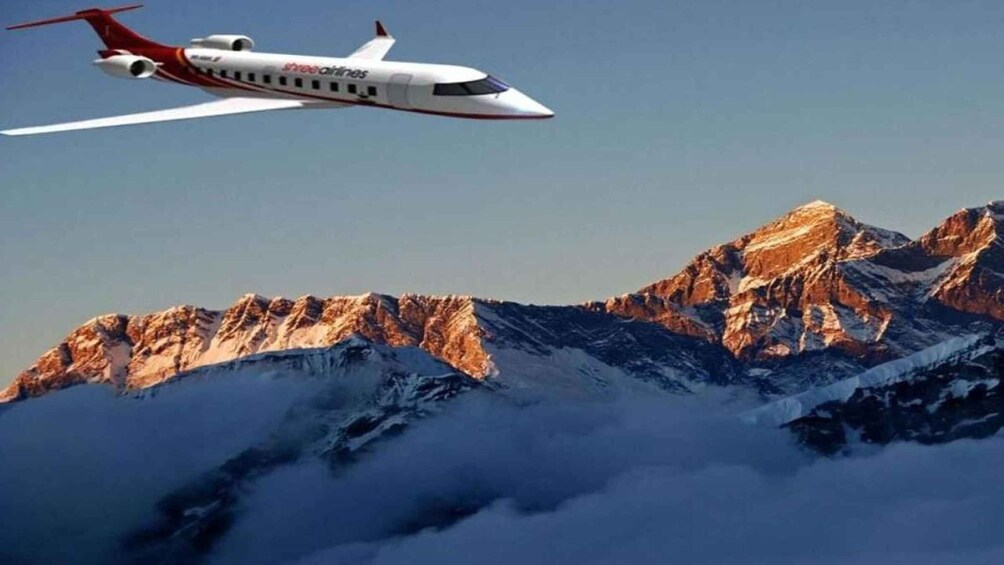 A commercial airplane flying over a mountainous landscape. 5