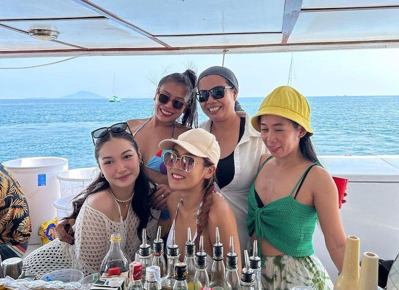 A group of people on a boat with bottles and a clear view of the sea. 3