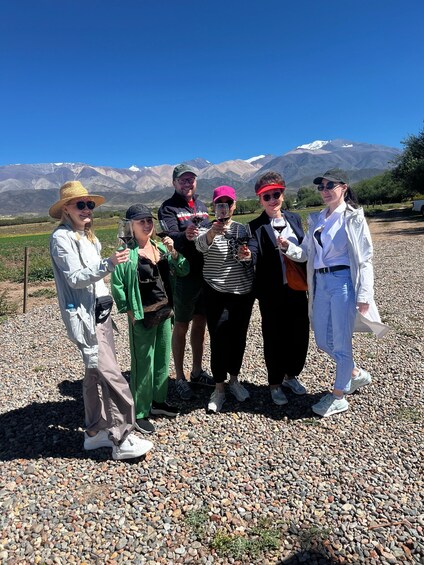 A group of people standing on a gravel path with a mountainous landscape in the background. 2