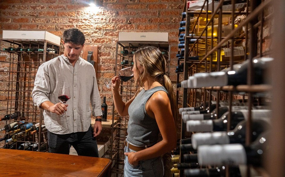 A man and a woman in a wine cellar with wine racks and bottles. 3