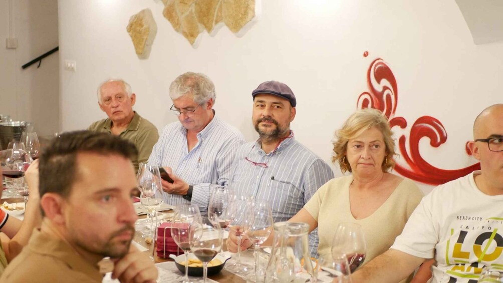 A group of people seated at a table with wine glasses and plates, suggesting a social gathering or event. 5