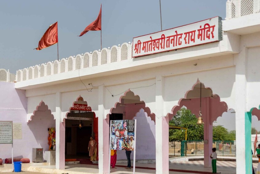 A temple entrance with a signboard, flags, and traditional architecture. 2