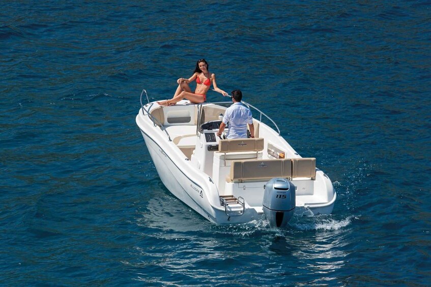 A white motorboat with a woman in a red bikini and a man in a white shirt on the deck. 4