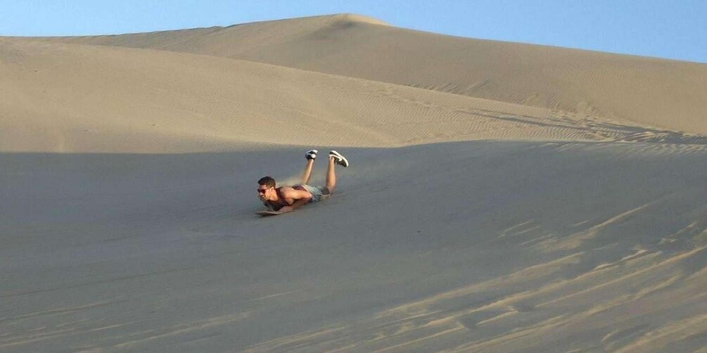 A person sliding down a sand dune. 5