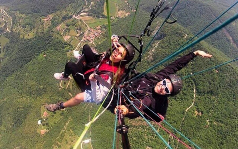 Two people skydiving with parachutes, surrounded by a mountainous landscape. 4