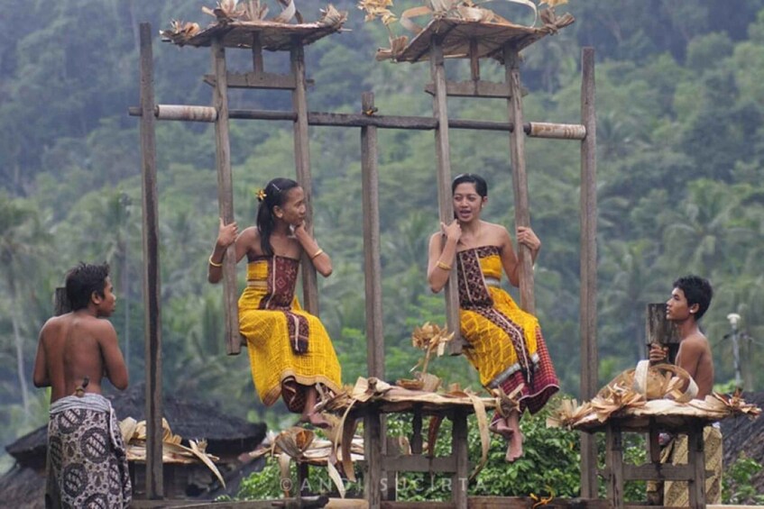 Una tradizionale esibizione di danza con ballerini in costumi colorati su un palco di legno, con una rigogliosa foresta sullo sfondo. 5