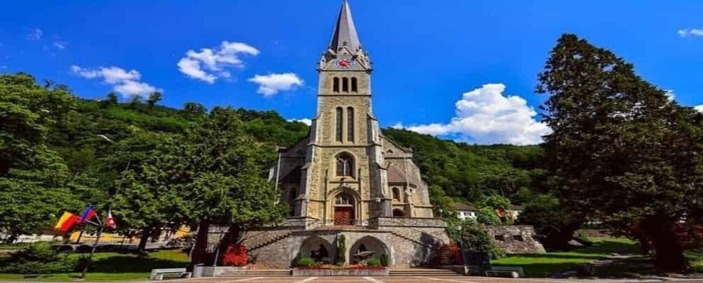 A church with a tall steeple, surrounded by trees and a clear sky. 4