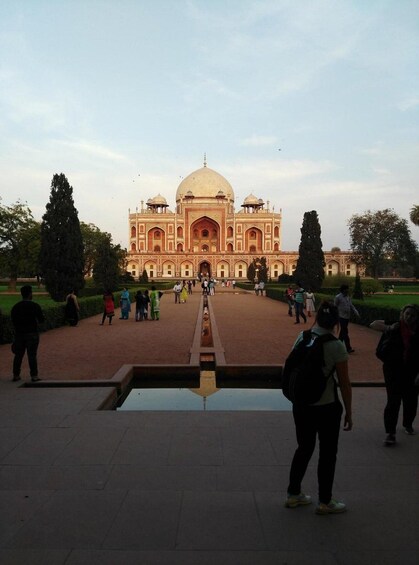 A large, historic building with a central dome and multiple smaller domes, surrounded by a well-maintained garden and a paved walkway. 4