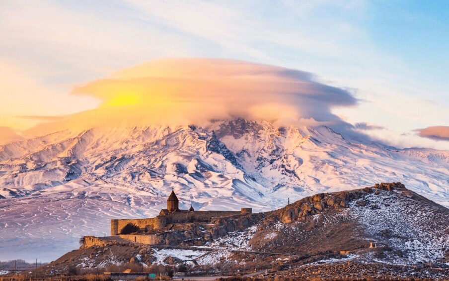 A snow-covered mountain with a castle and a sunset in the background. 5