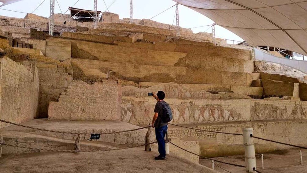 A person taking a photo inside an ancient amphitheater with stone steps and a large open area. 2