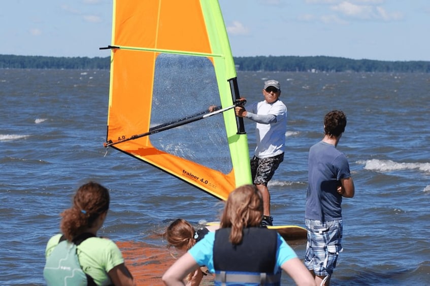 A person windsurfing on a lake with a bright orange sail. 5