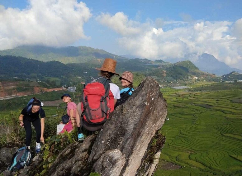 A group of hikers on a mountain trail with terraced fields in the background. 3