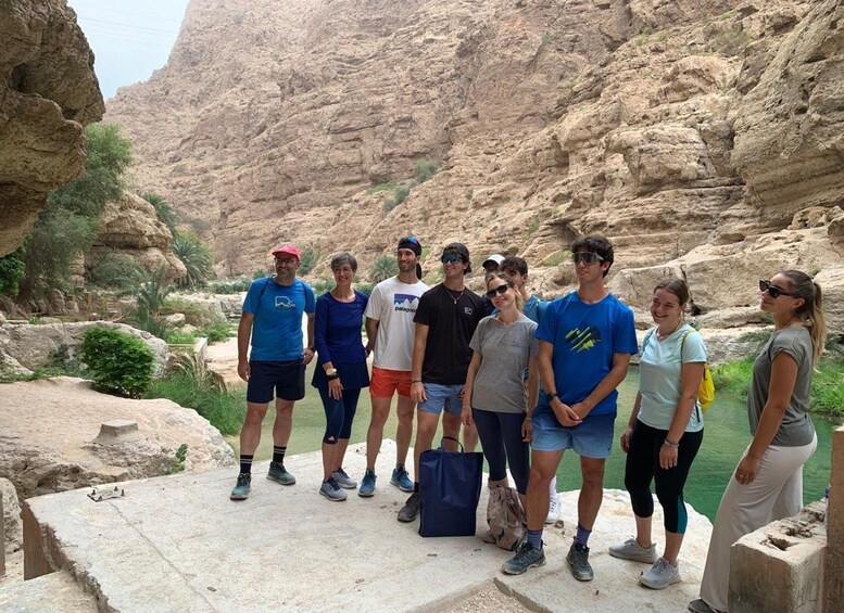 A group of people standing on a stone platform overlooking a canyon with rocky cliffs and greenery. 5