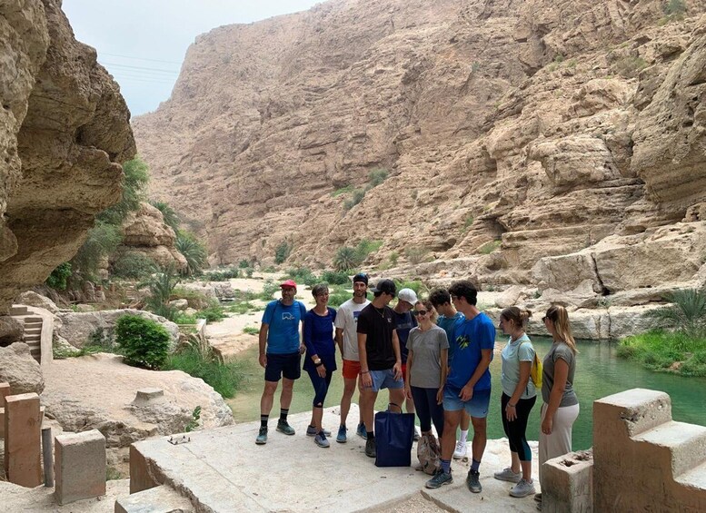 A group of people standing on a concrete platform overlooking a canyon with a river. 3