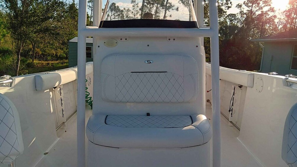 A boat's interior with a white cushioned seat, a control panel, and a window. 5