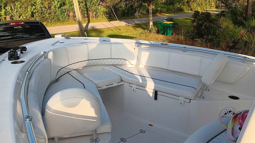 A boat interior with a cushioned seating area, a steering wheel, and a small table. 3