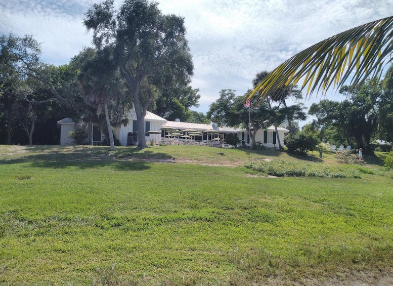 A white house with a porch, surrounded by trees and a grassy yard. 2
