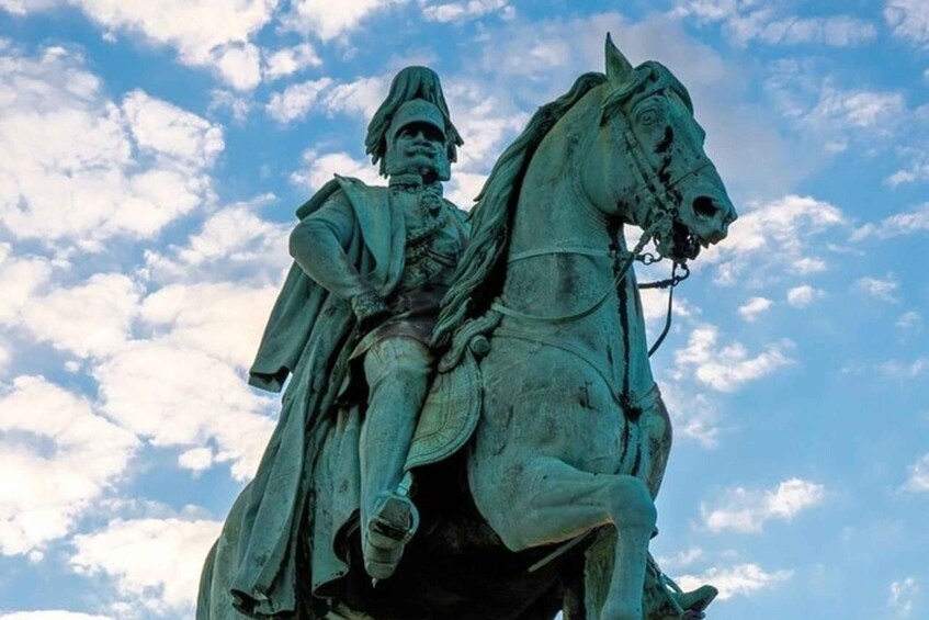 A bronze statue of a man on horseback against a blue sky with clouds. 3