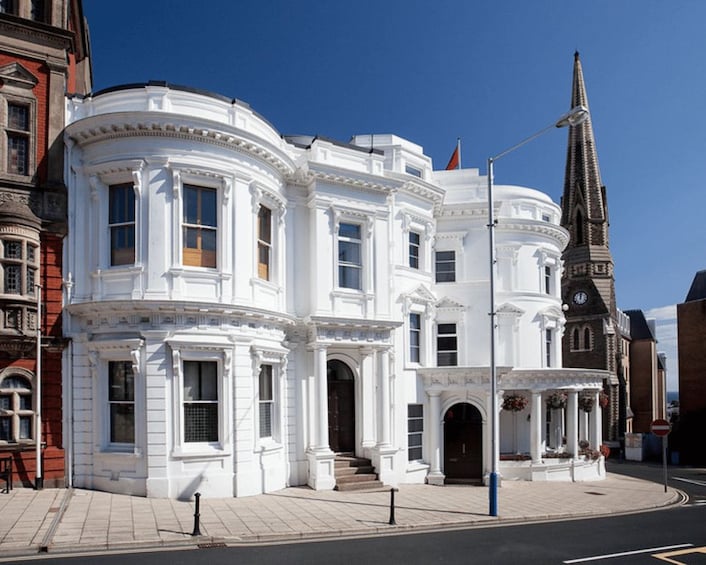 A white building with arched windows and a clock tower. 2