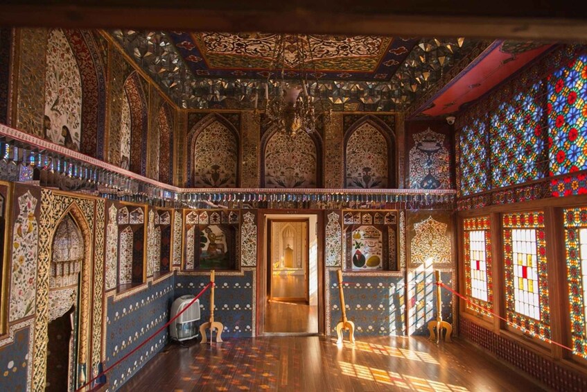 An ornate interior with intricate tile work, a chandelier, and stained glass windows. 5