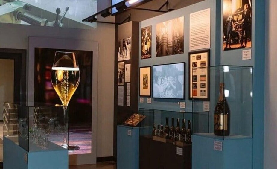 A museum exhibit with wine glasses, bottles, and informational posters. 1