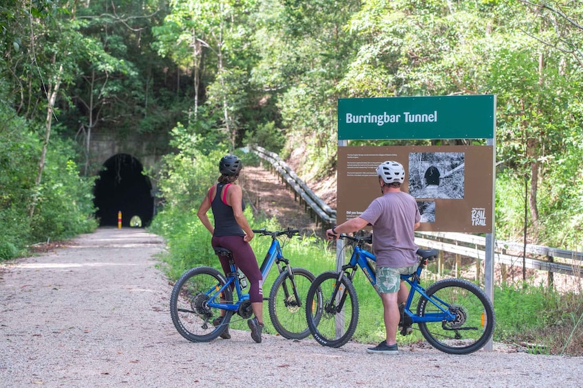A dirt path leading to a tunnel with cyclists and a sign for Burringbar Tunnel. 3