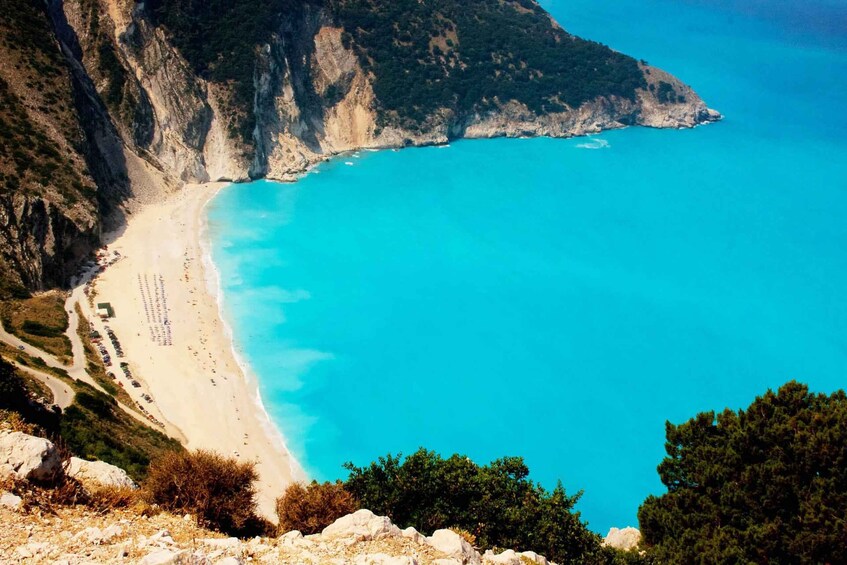 A coastal landscape with a beach, cliffs, and a clear blue sea. 4