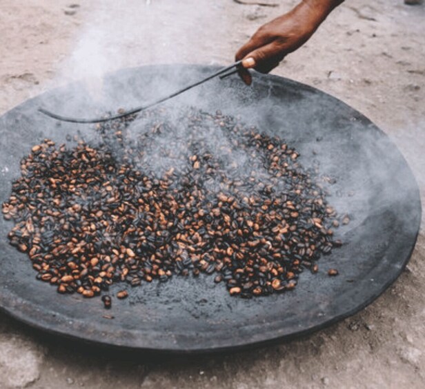 A person roasting coffee beans on a flat surface. 2