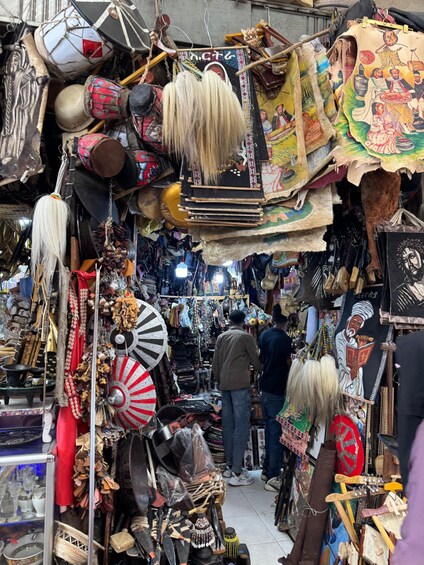 A crowded market with various items like drums, textiles, and jewelry. 4