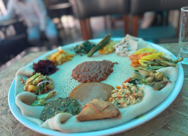 A traditional Ethiopian meal on a large plate with injera, various stews, and vegetables. 1