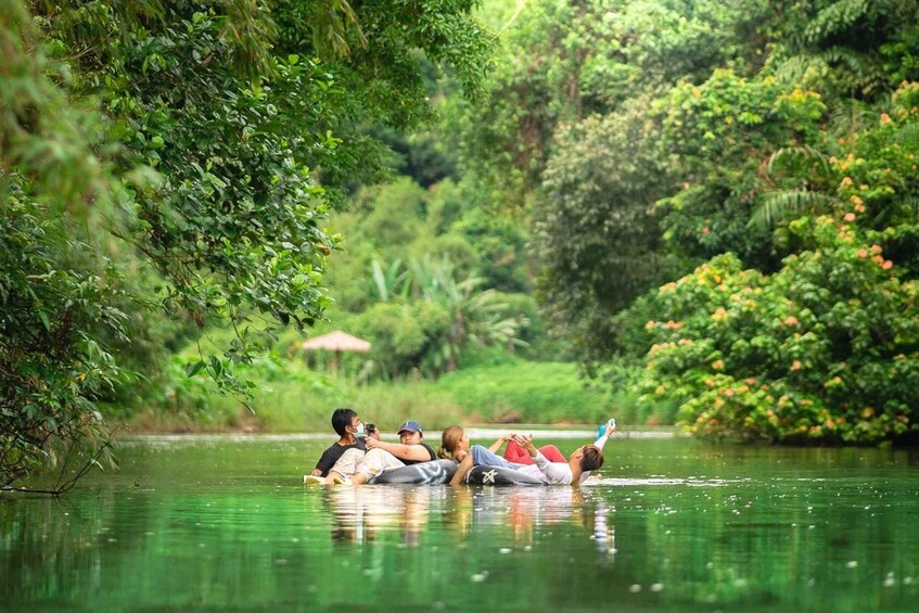 A group of people floating on a calm river surrounded by lush greenery. 1