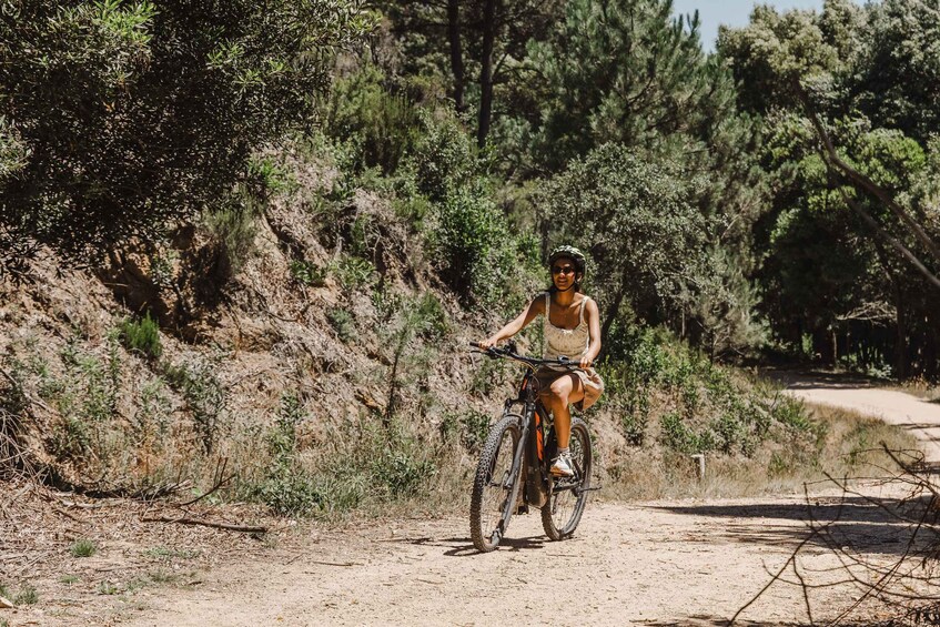 A person riding a mountain bike on a dirt path surrounded by trees. 2