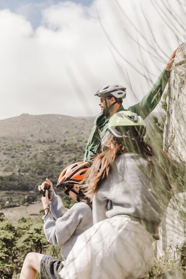 A person climbing a rock wall with a helmet and another person taking a photo. 5