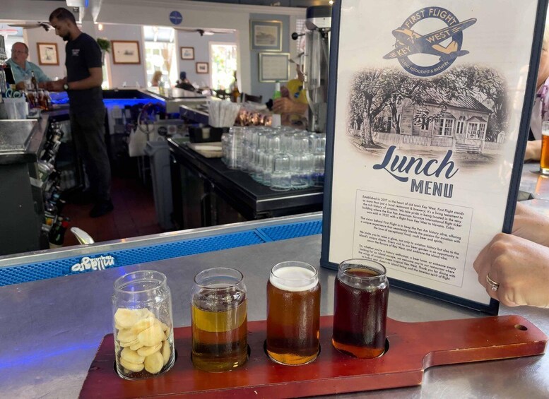 A bar with a 'Lunch Menu' sign, glasses of beer, and a jar of sliced bananas on a tray. 3