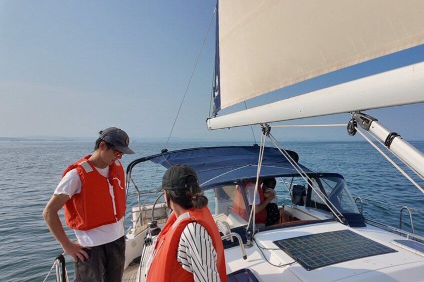 A sailboat with two people wearing life jackets standing at the bow. 4