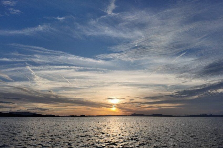 A sunset over a calm body of water with a clear horizon and distant landforms. 3