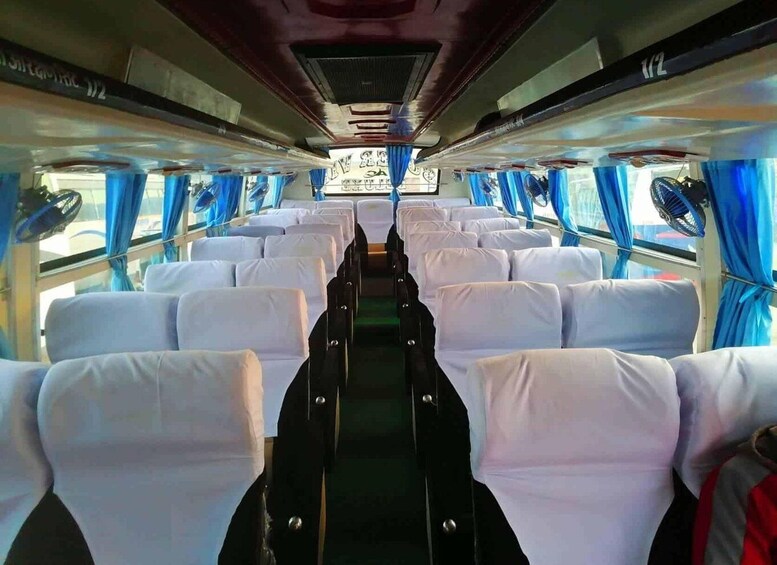 A train interior with rows of white seats and blue curtains. 2