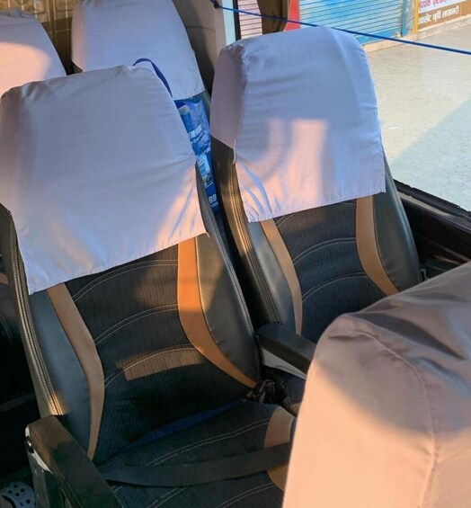 A bus interior with two seats covered in white cloths and a blue bottle in the back. 1
