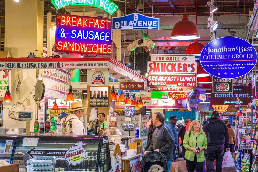 A busy market with various food stalls, including signs for breakfast and sausage sandwiches, and a butcher shop. 5