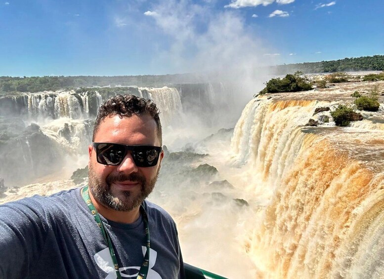 A person taking a selfie with a waterfall in the background. 1