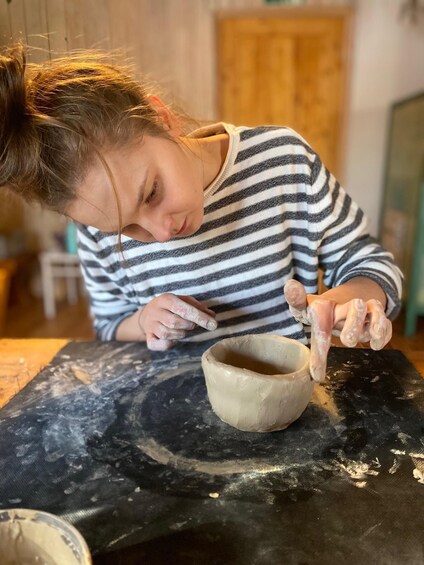 A person shaping a clay pot on a pottery wheel. 2