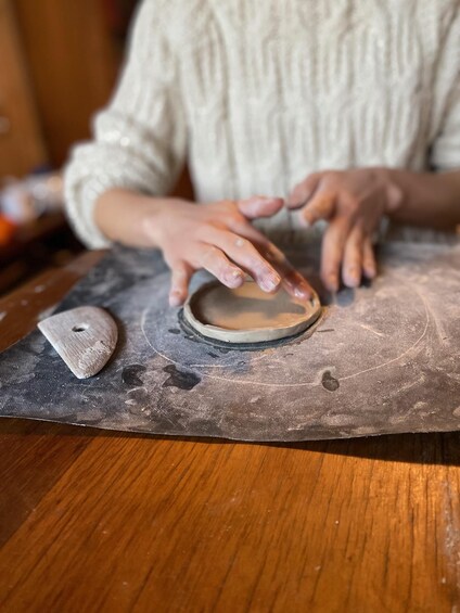 A person shaping a clay pot on a wooden surface. 1