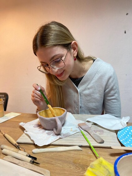 A person stirring a yellow liquid in a ceramic mug. 3