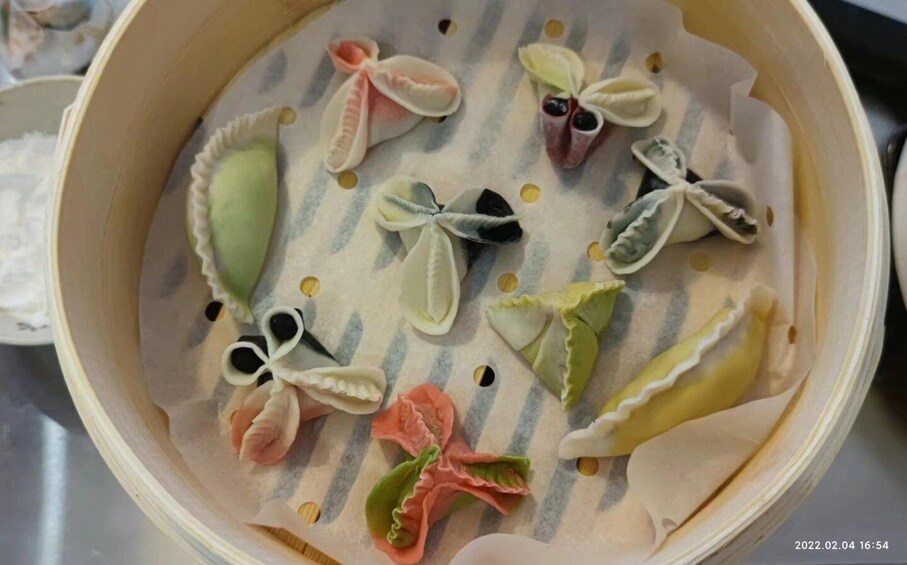 A steamer basket with various dumplings in different shapes and colors. 2