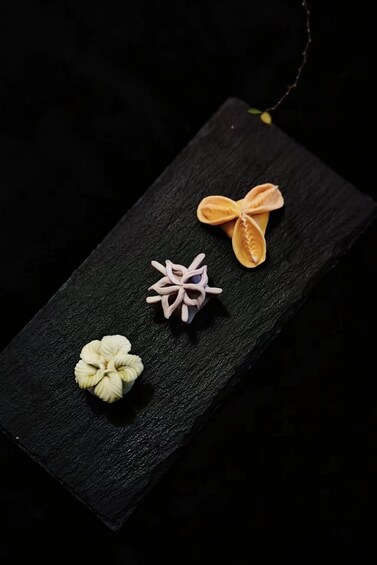 A black rectangular object with three decorative items: a white flower, a pink star, and an orange butterfly. 5