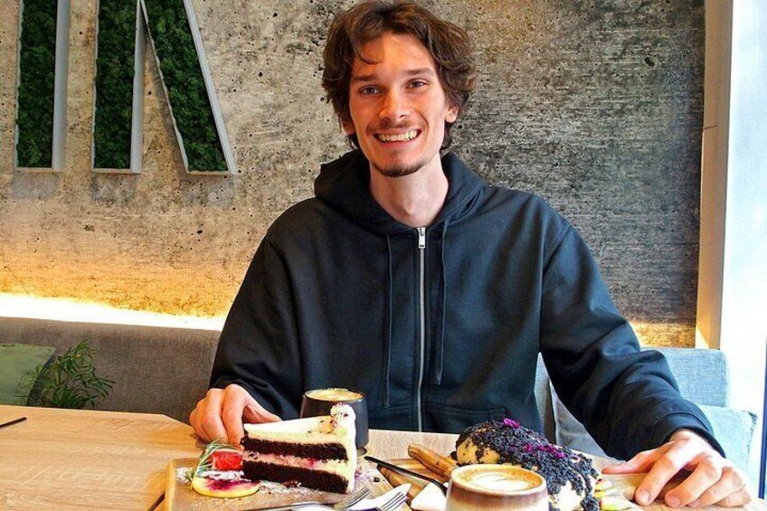 Een persoon zit aan een tafel met taart en een kop koffie. 3