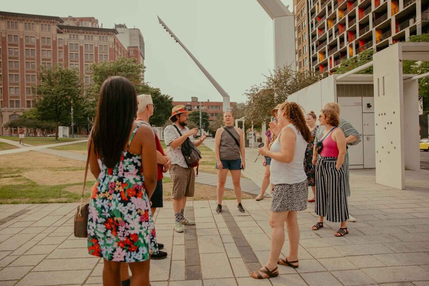 A group of people standing on a paved area with buildings in the background. 2